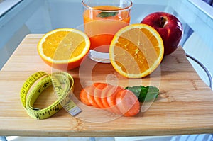 Lose weight, fresh fruits and a glass of orange juice on a wooden board.