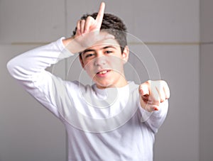 Loser gesture by blurred smooth-skinned Hispanic teen on industr