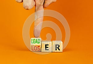 Loser or leader symbol. Businessman turns wooden cubes and changes the word Loser to Leader. Beautiful orange table orange