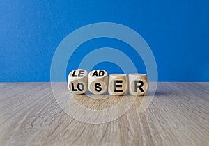 Loser or leader symbol. Turned cubes and changes the word loser to leader. Beautiful wooden table, blue background. Business and