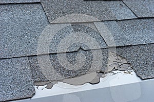Ð¡loseup view of asphalt shingles roof damage that needs repair.