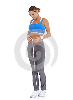 Losing inches and feeling proud. Young woman in sportswear measuring her waistline while isolated on white.