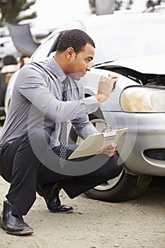 Loss Adjuster Taking Photograph Of Damage To Car