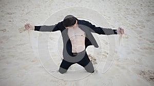 Loss, concept. young man kneeling in the desert. Sand through fingers