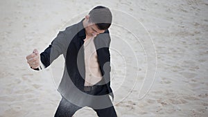 Loss, concept. young man kneeling in the desert. Sand through fingers