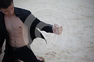 Loss, concept. young man kneeling in the desert. Sand through fingers