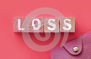 Loss word on wooden blocks with pink wallet besides on warm pink background. Risky investments., debts. or financial loss in