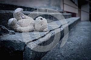 Lost childhood, loneliness and pain concept. Dirty teddy bear lying down outdoors