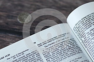 Lost coin parable verses in open holy bible book placed on wooden background