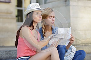 Lost and confused girl friends looking for directions on map