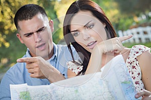 Lost and Confused Mixed Race Couple Looking Over Map Outside