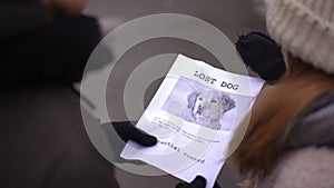 Lost dog announcement in hands of teen girl and boy standing outdoors. Shooting over shoulder of teenage Caucasian