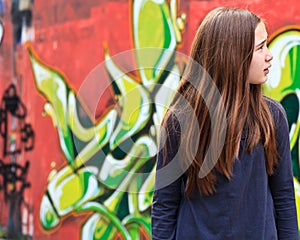 Lost girl by a graffiti wall