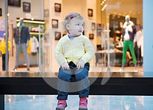 Lost girl sitting on bench in mall