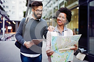 Lost happy couple in the city holding a map. Travel, tourism, people concept