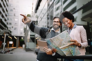 Lost happy couple in the city holding a map. Travel, tourism, people concept