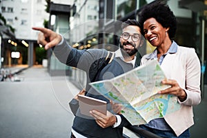 Lost happy couple in the city holding a map. Travel, tourism, people concept