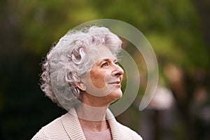 Lost in happy memories. a senior woman deep in thought while standing outside.