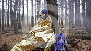 Lost hiker woman wrapped on golden survival blanket