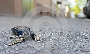 The lost keychain, car alarm remote, lies on the asphalted sidewalk of the road