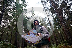 Lost, man and search forest with map as guide to camp in woods and thinking of navigation or direction. Confused, travel