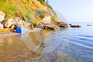 Lost plastic blue barrel on sandy beach