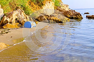 Lost plastic blue barrel on sandy beach