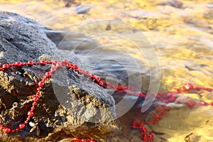 lost red beads decorate a stone glaring in the bright sun