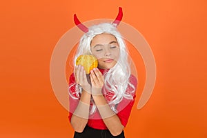 Lost in thoughts. jack o lantern. happy halloween. kid wear devil horns. child with pumpkin. teen girl wear long curly