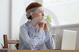 Lost in thoughts woman sits at workplace desk in office