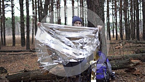 Lost tourist woman uses Golden survival blanket in forest