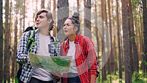 Lost tourists are standing in forest looking at map, talking and gesturing then finding way and walking to destination