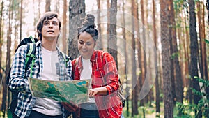 Lost tourists are standing in forest looking at map, talking and gesturing to finding way . People, travelling and