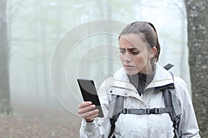 Lost trekker checking gps on smart phone in nature