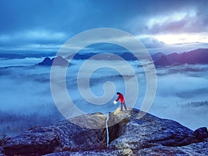 Lost woman hold in hands shining lamp on mountain peak