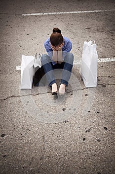 Lost woman sitting in parking lot with bags photo