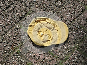 lost yellow cotton cap on a brick street