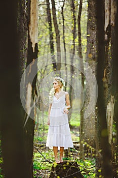 Lost young woman with blond hair in white dress forest among trees.