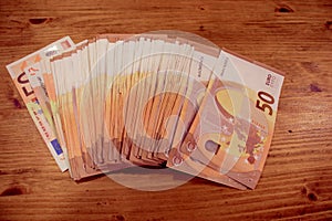 A lot of 50 euro banknotes in a row on a wooden table