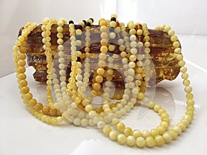 A lot of Baltic amber white beads lie on a piece amber.