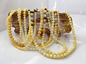 A lot of Baltic amber white beads lie on a piece amber