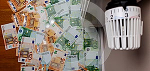 A lot of banknotes of 50 and 100 euros, in the background is the thermostat of the radiator battery