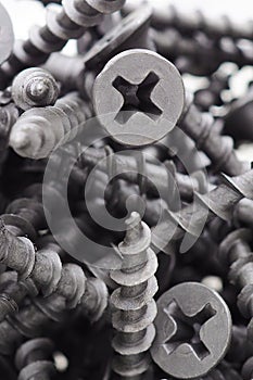 A lot of black big screws lie in a pile on a white background. Close-up. Hardware, fasteners, ironware, ironmongery, materials for photo