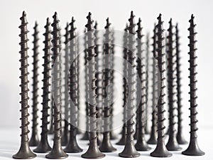 A lot of black long screws stand upright on a white background. Close-up. Hardware, ironware, ironmongery, fasteners, materials