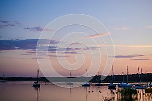 A lot of boats sailing along the river in the sunset