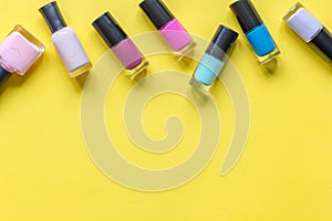 Lot of bottles nail polish on yellow background top view