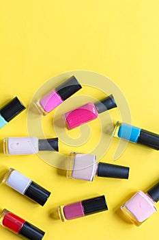 Lot of bottles nail polish on yellow background top view