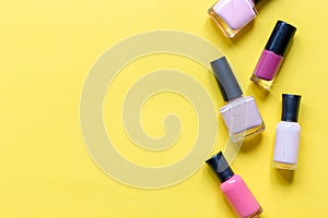 Lot of bottles nail polish on yellow background top view