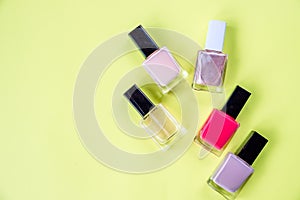 Lot of bottles nail polish on yellow background top view.hands care concept with nail polish yellow desk background top