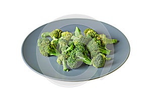 Lot of branches of fresh green broccoli on round gray plate isolated on white background without shadow
